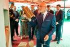 mężczyzna stoi przy ścianie, trzyma w ręku cegłę, za nim stoi kilka osób