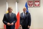 Marszałek i Dyrektor Kurczab stoją na tle flag, herbu i godła