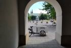 biała przyczepa rowerowa wypełniona książkami na tle łuku krakowskiej kamienicy