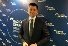 Wicemarszałek Łukasz Smółka stoi na tle ściany z napisem Radio Kraków.