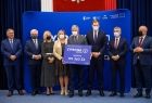 Grupa gości wydarzenia stoi na podwyższeniu razem z przedstawicielem gminy Iwkowa, wśród nich wicemarszałek Józef Gawron