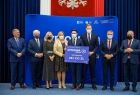 Grupa gości wydarzenia stoi na podwyższeniu razem z przedstawicielem gminy Szczurowa, wśród nich wicemarszałek Józef Gawron