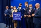 Grupa gości wydarzenia stoi na podwyższeniu razem z przedstawicielem gminy Gręboszów, wśród nich wicemarszałek Józef Gawron
