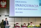 Wicemarszałek Łukasz Smółka przemawia z mównicy. Na ścianie godło Polski i napis o treści Uroczysta Inauguracja 69. roku akademickiego 2021/2022.