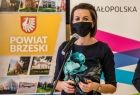 Marta Malec-Lech z zarządu województwa przemawia do uczestników uroczystości. W tle baner z napisem Powiat Brzeski i Małopolska.