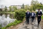 Grupa osób idzie alejką wzdłuż stawu
