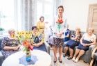 Marta Malec-Lech z zarządu województwa wraz z seniorami, stoi i w dłoniach trzyma kwiat.