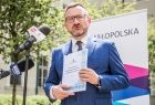 Wicemarszałek Tomasz Urynowicz na tle banneru z napisem Małopolska