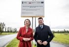 Wicemarszałek Łukasz Smółka i Marta Malec-Lech stoją na nowej drodze w Bochni. Z tyłu widoczna tablica informacyjna ze środkami unijnymi.