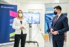 Kobieta i mężczyzna stoją w szpitalnym korytarzu na tle bannerów podczas spotkania z mediami