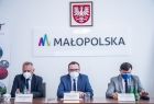 Grzegorz Biedroń, Tomasz Urynowicz i Rafał Kosowski podczas konferencji, w tle logo Małopolski
