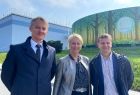 Trzy osoby stoją na chodniku przed budynkiem oczyszczalni ścieków