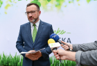 Wicemarszałek Tomasz Urynowicz udziela wypowiedzi mediom podczas konferencji prasowej dotyczącej Programu Ochrony Powietrza, w tle banner ekoMałopolska