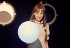 Kobieta w stroju kosmonauty trzyma w ręku świecącą kulę