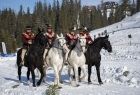 W zimowej scenerii, na zewnątrz. na koniach jadą mężczyźni w strojach góralskich