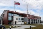 Nowoczesna remiza straży pożarnej w Dąbrowie Tarnowskiej. Na pierwszym planie maszt z flagą Polski.