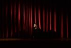 Mężczyzna na scenie teatralnej. Patrzy w reflektor