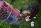 Dziewczynka maluje kolorowymi farbami beczkę po ropie