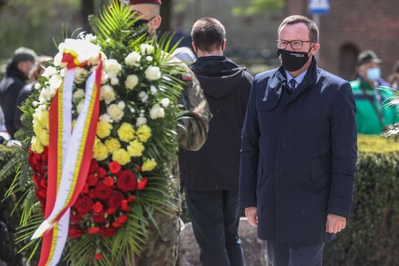 Wicemarszałek Tomasz Urynowicz składa wieniec przed Grobem Nieznanego Żołnierza. Na pierwszy planie żołnierz trzymający wieniec.