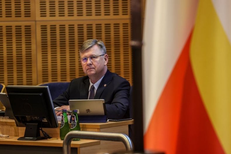 Marszałek Witold Kozłowski siedzi przed monitorem na sali sesyjnej.