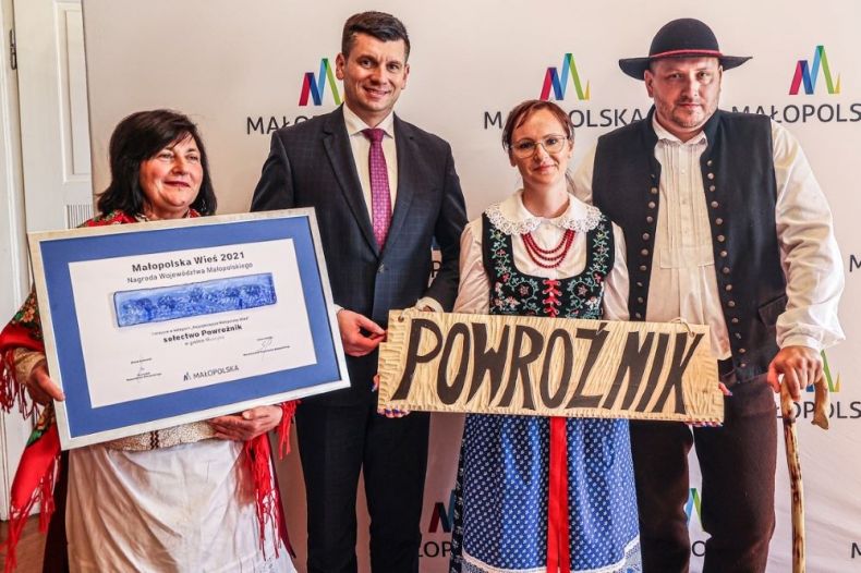 Wicemarszałek Łukasz Smółka stoi z przedstawicielami sołectwa Powroźnik. Ubrani są oni w stroje ludowe.