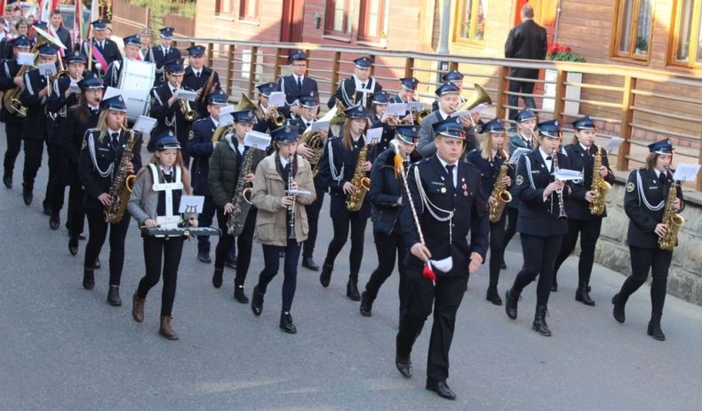 Strażacka Orkiestra Dęta Filipowice maszeruje ulicą i gra.