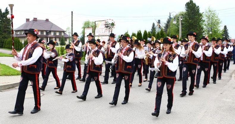 Parafialno-Gminna Orkiestra Dęta z Łososiny Dolnej maszeruje ulicą i gra.