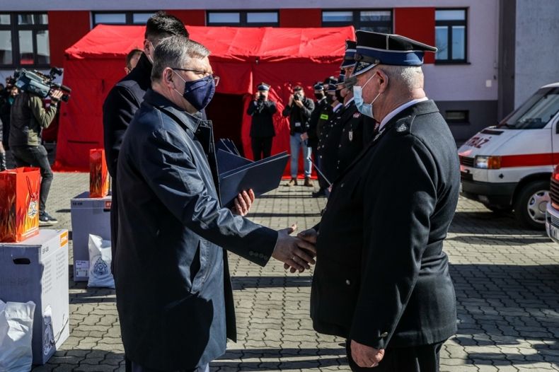 Marszałek Witold Kozłowski wręcza przedstawicielowi straży pożarnej akt przekazania namiotu - widok z boku