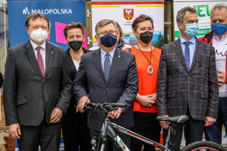 kilka osób pozuje do zdjęcia m.in. marszałek Witold Kozłowski, który trzyma rower