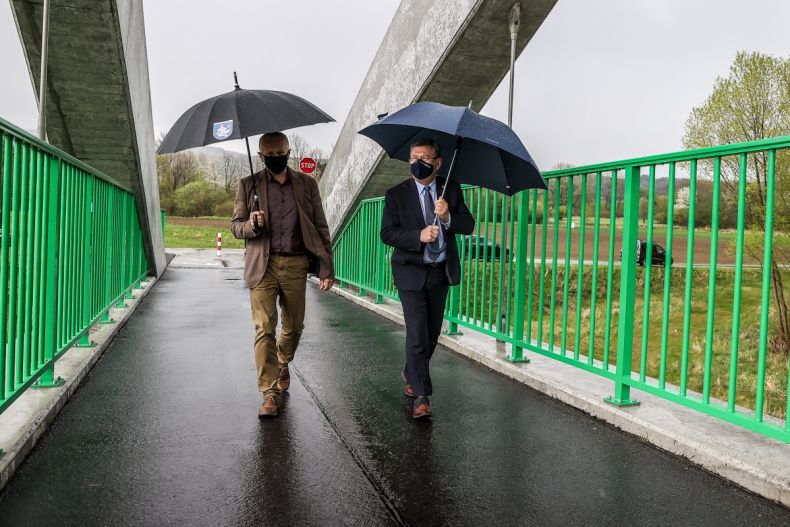 wójt Jan Dziedzina i marszałek Witold Kozłowski na kładce VeloDunajec w Łącku. Idą pod parasolami