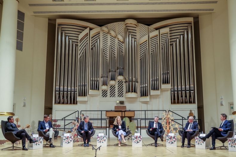 Uczestnicy debaty siedzą na fotelach na scenie