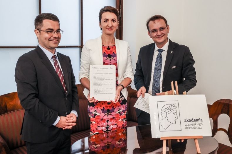 Marta Malec-Lech z zarządu województwa stoi, w dłoniach trzyma podpisaną umowę. Obok znajdują się prof. dr hab. Andrzej Betlej dyrektor Zamku Królewskiego na Wawelu i dr Łukasz Cieślik dyrektor Małopolskiego Centrum Doskonalenia Nauczycieli.