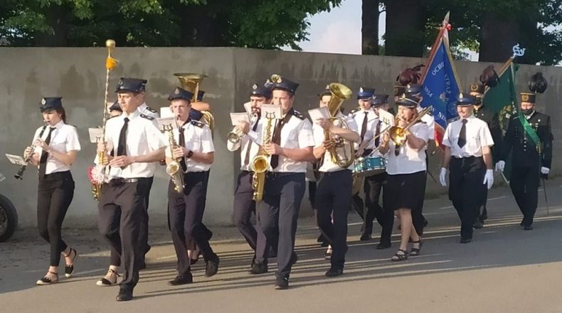 Orkiestra Dęta OSP Nidek podczas przemarszu ulicą gra.