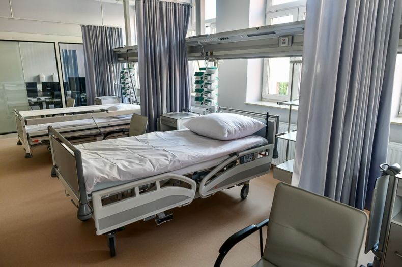 Nowoczesna sala szpitala, widoczne łóżka i sprzęt medyczny.