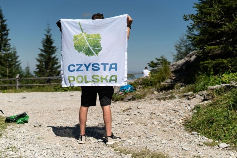 Mężczyzna trzyma flagę z logo akcji "Czyste Tatry"