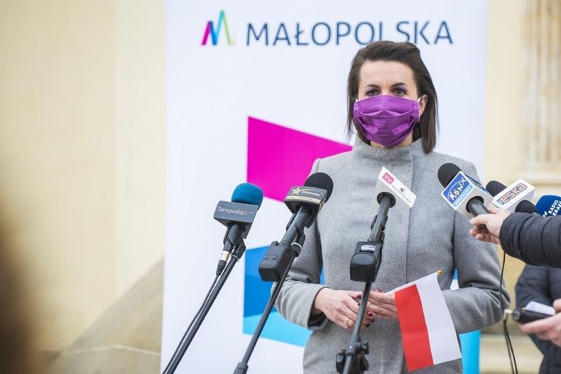 Marta Malec-Lech z zarządu województwa stoi i mówi do mikrofonu. W tle widoczny napis Małopolska.