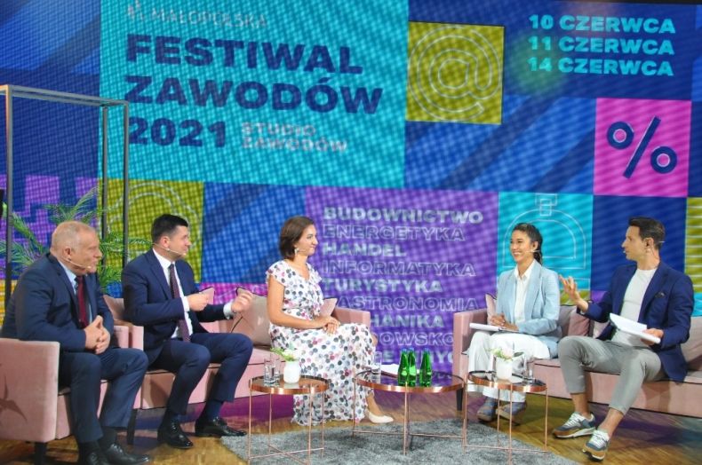 Dyskusja otwierająca program drugiego dnia festiwalu: pięć osób siedzi na kanapach na tle ekranu interaktywnego z nazwą Festiwalu Zawodów