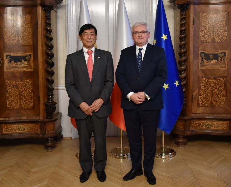 Wicemarszałek Józef Gawron stoi w gabinecie z ambasadorem Japonii w Polsce Akio Miyajimą. W tle widoczne zabytkowe meble i flagi Małopolski, Polski i Unii Europejskiej.