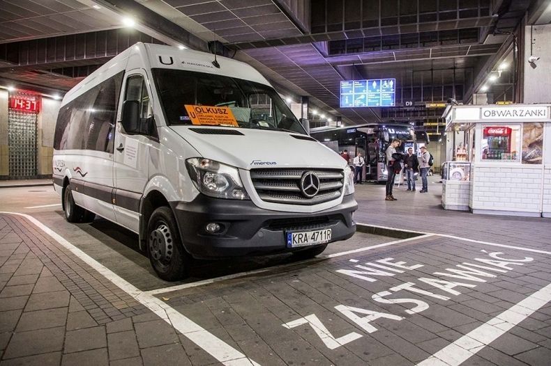 Mały autobus stoi na dworcu autobusowym. Przed nim namalowany napis Nie Zastawiać.