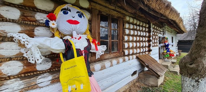Kukła Małopolskiej Marzanny oparta o drewnianą chatę na terenie Skansenu Wsi Pogórzańskiej w Szymbarku