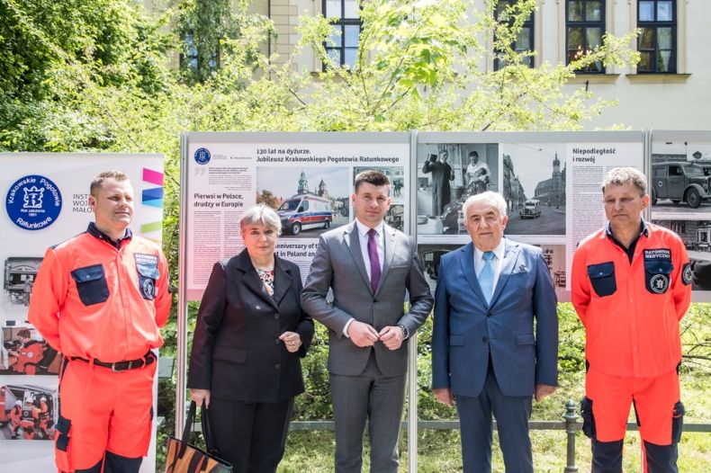 Wicemarszałek Łukasz Smółka stoi z uczestnikami wydarzenia, z tyłu widoczna wystawa.