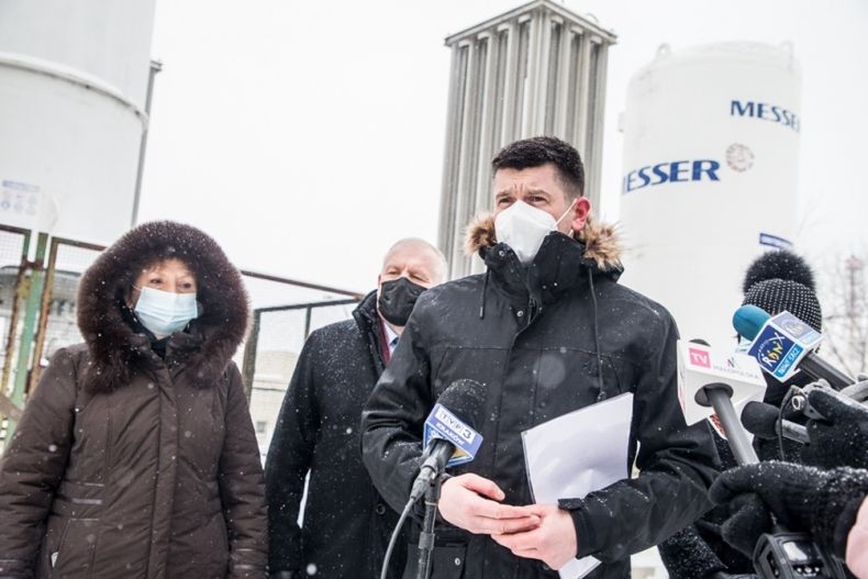 Wicemarszałek Łukasz Smółka, wicewojewoda Ryszard Pagacz oraz dyrektor szpitala Anna Czech w trakcie spotkania z prasą. Spotkanie odbywa się przed zbiornikami z tlenem. Przemawia wicemarszałek Łukasz Smółka