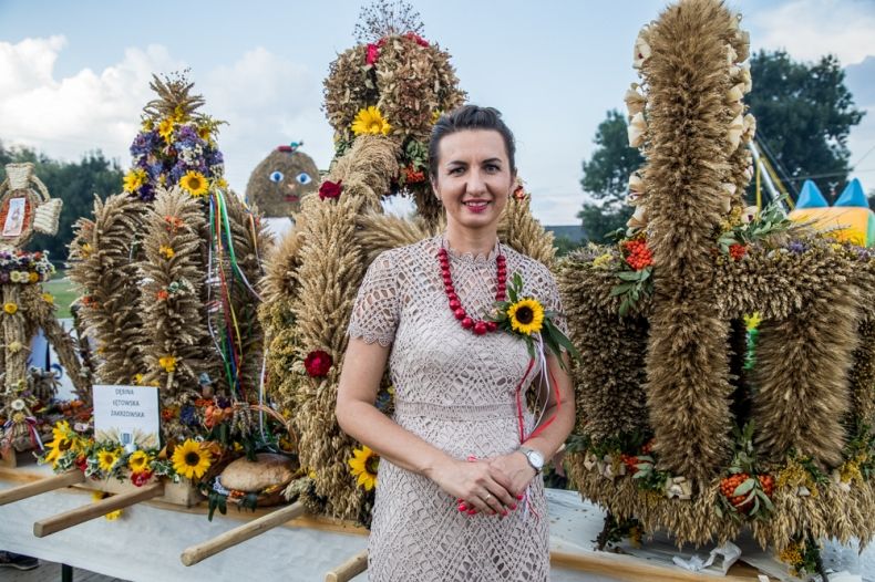Marta Malec-Lech z zarządu województwa na tle wieńców dożynkowych.