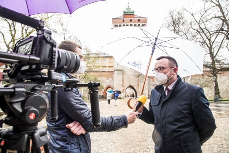 Wicemarszałek Tomasz Urynowicz rozmawia z reporterem, w tle widoczna Brama Floriańska