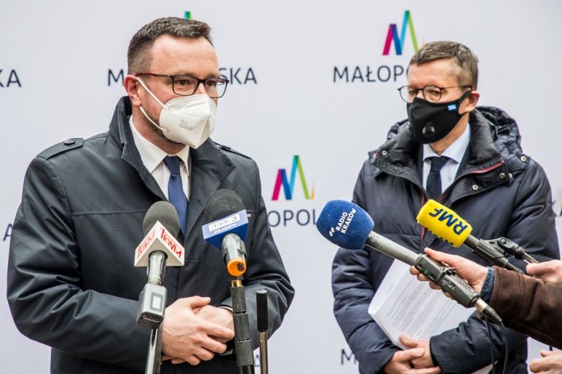 Wicemarszałek Małopolski Tomasz Urynowicz i Robert Tomanek - Podsekretarz Stanu w Ministerstwie Rozwoju, Pracy i Technologii stoją na tle banneru Małopolski. Wicemarszałek mówi do mikrofonu