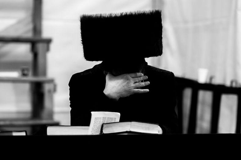 Zdjęcie czarno-białe autorstwa Andrzeja Błońskiego, przedstawiające żyda chasydzkiego w futrzanej czapie czytającego książkę.