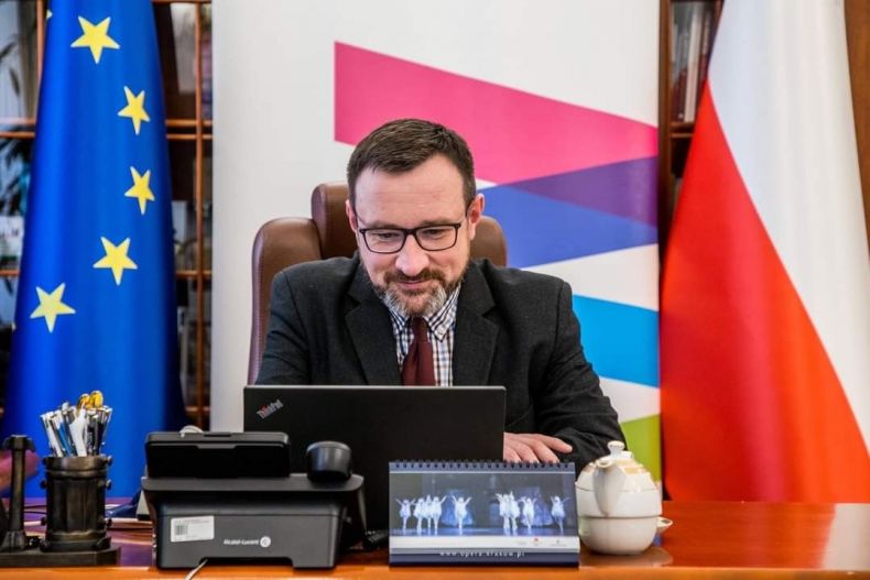 Wicemarszałek Tomasz Urynowicz siedzi przy biurku, patrzy w ekran laptopa