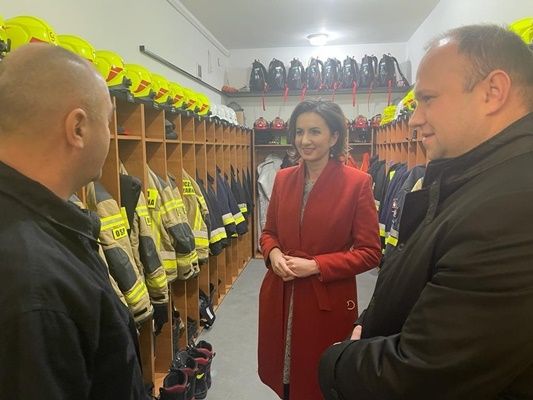 Marta Malec-Lech z zarządu województwa stoi ze strażakami w szatni.