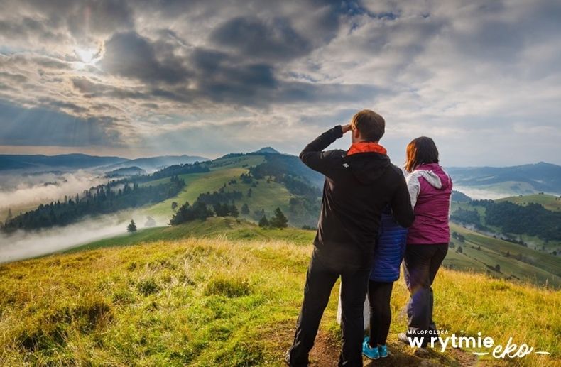 Rodzina na szczycie wzniesienia górskiego, w tle górski krajobraz