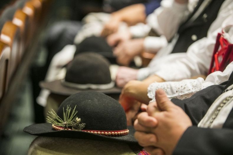 Osoby siedzące w rzędzie z góralskimi kapeluszami na kolanach